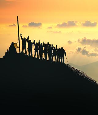 Teamwork. A group of people are standing on the top of the mountain.
